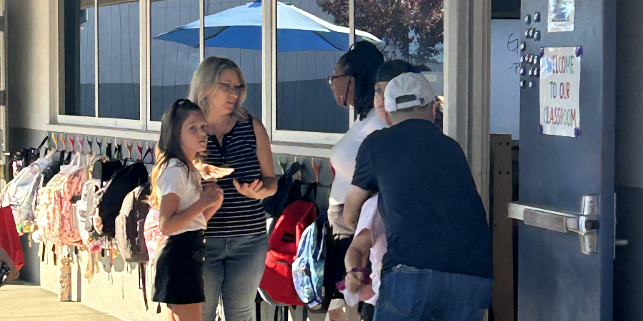 Photo of students talking with teacher on first day of school 